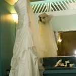 Wedding dress and veil hanging in dressing area.