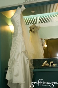 Wedding dress and veil hanging in dressing area.