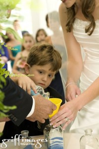 Bride's son pouring sand into the vase during the sand ceremony of the wedding.