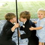 Two of the junior groomsmen and the ring bearer having fun with each other through the glass divider.