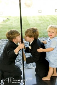 Two of the junior groomsmen and the ring bearer having fun with each other through the glass divider.